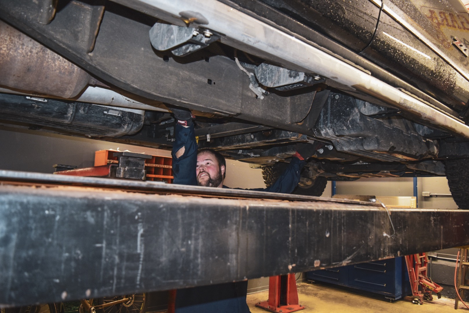 Employee performing a mechanical repair under a truck at 1st Street Garage